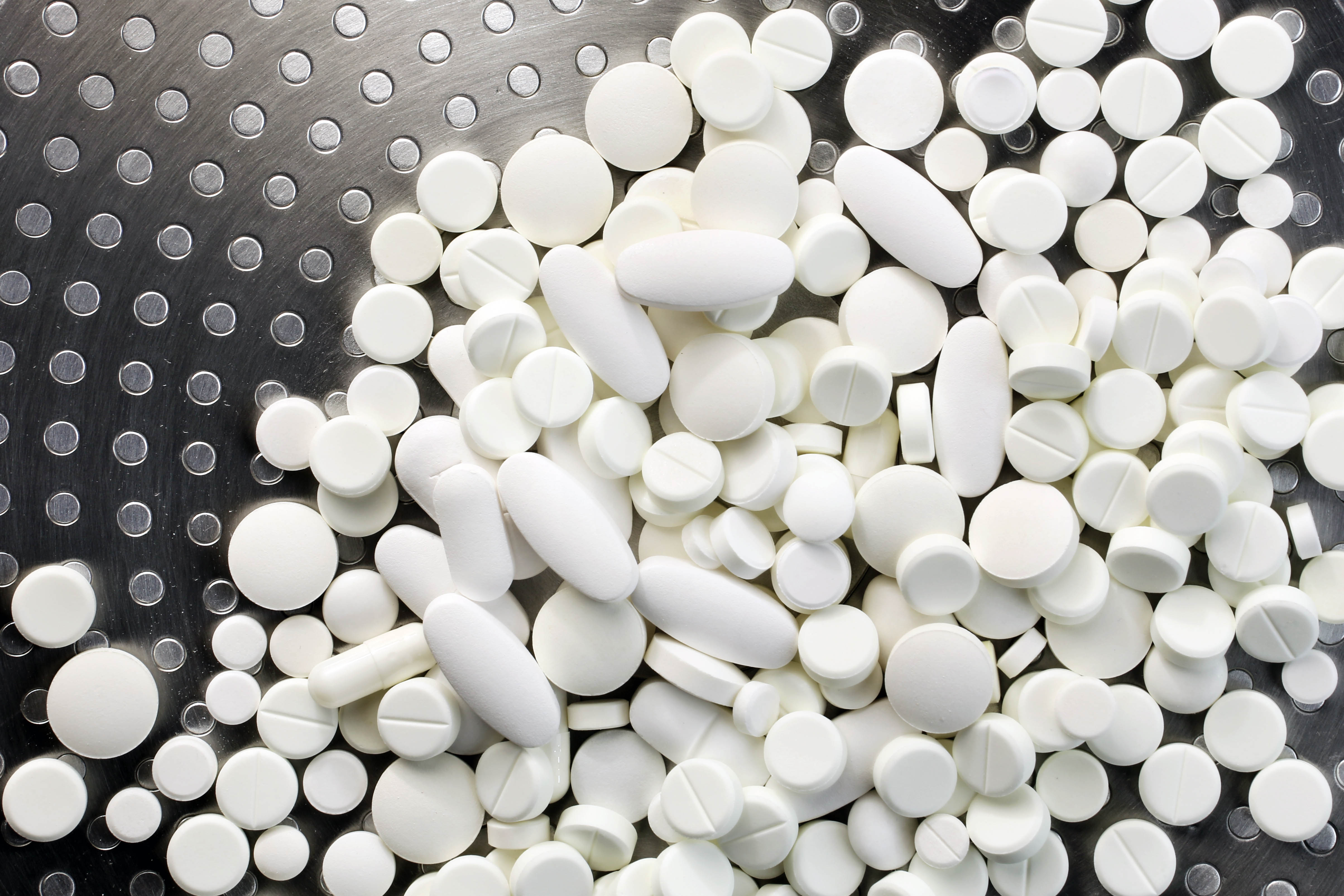 Prescription drug tablets on a black surface