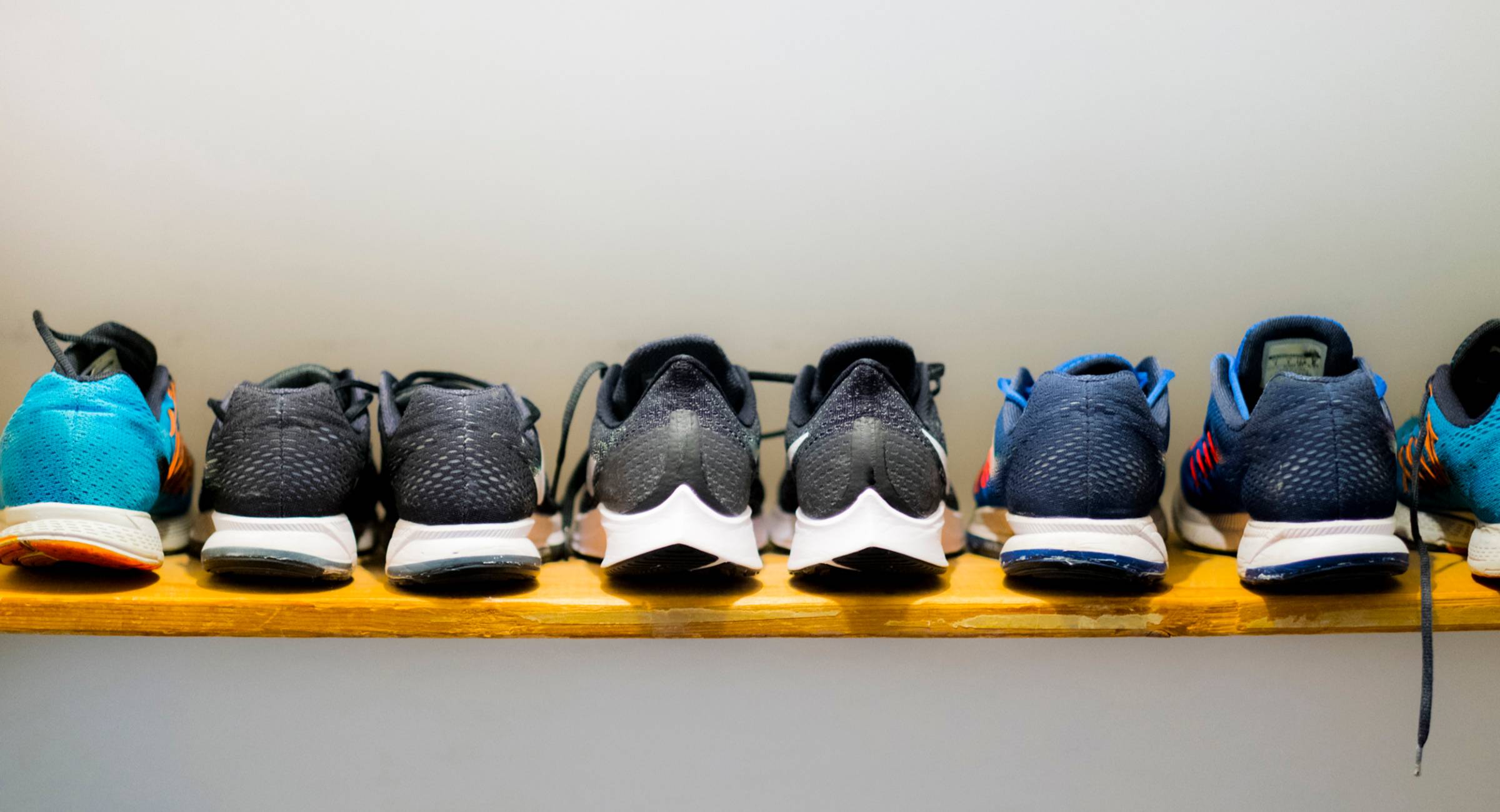 Sneakers neatly lined up against a white wall.