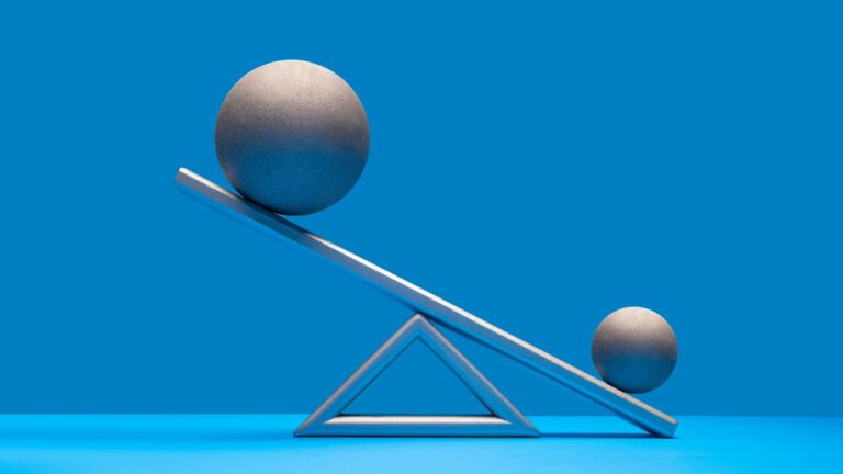3 factors to consider when choosing a prime broker, image is of a large ball tipping the scale of a small ball on the other end of a sea-saw like scale. Grey against a blue background.