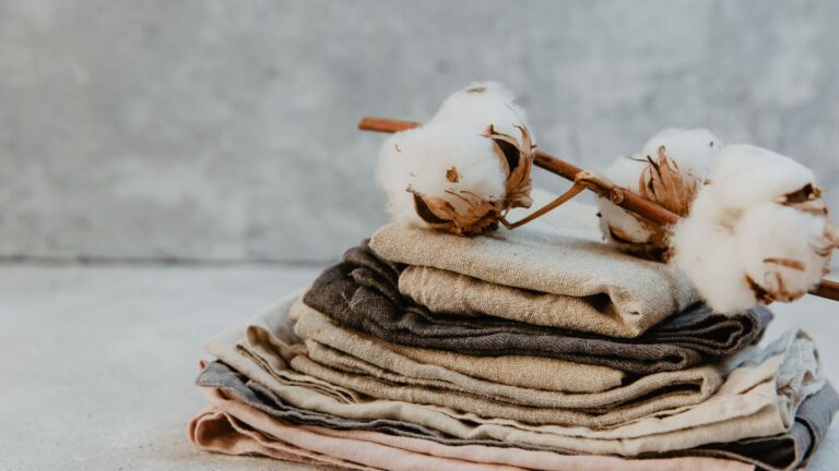 Chief Sustainability Officer, CSO Helene Smits and board member Samir Shah of Recover, discuss sustainability & circularity, & customer sentiment towards recycled cotton. Image is of freshly picked cotton set atop cotton linen against a light grey and white background. The linens are brown and rustic.