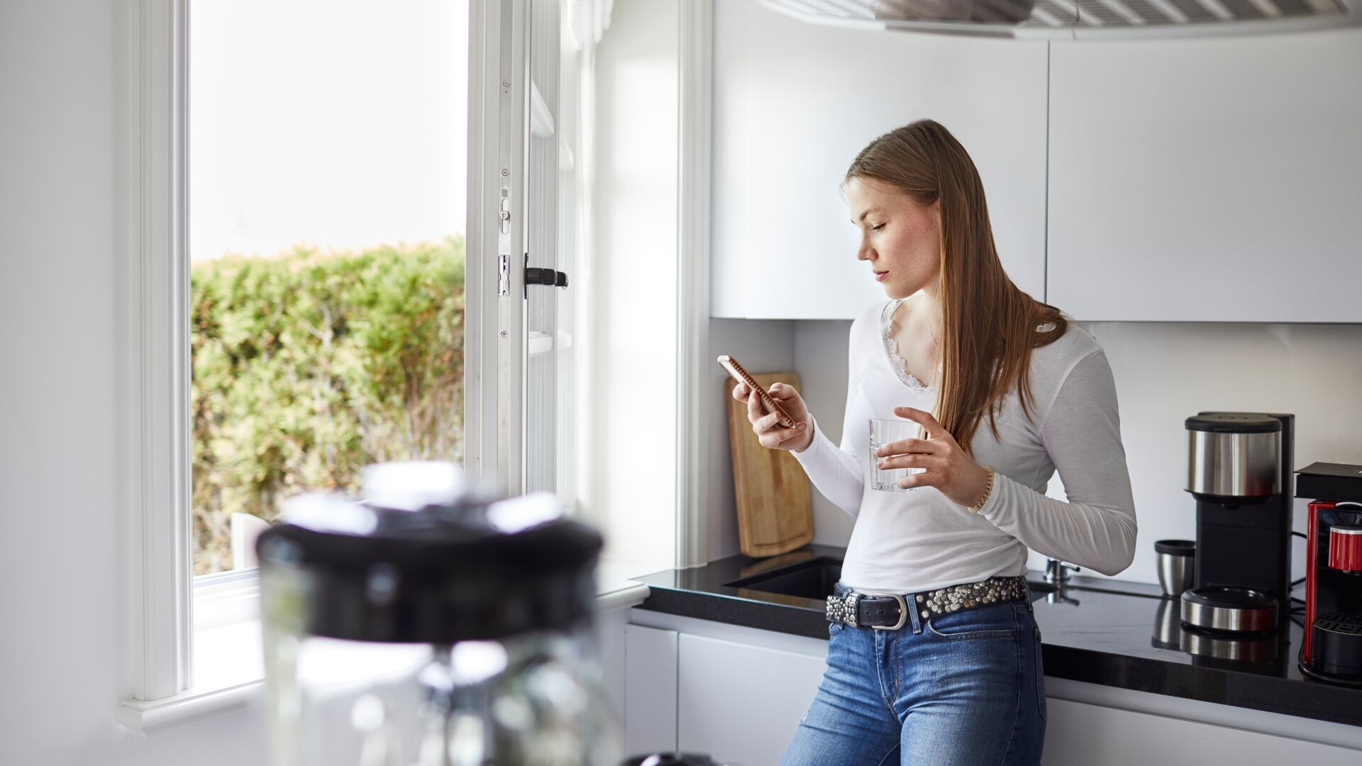 Image of woman using mobile device in her kitchen. Concept for digital health in the treatment of IBS.