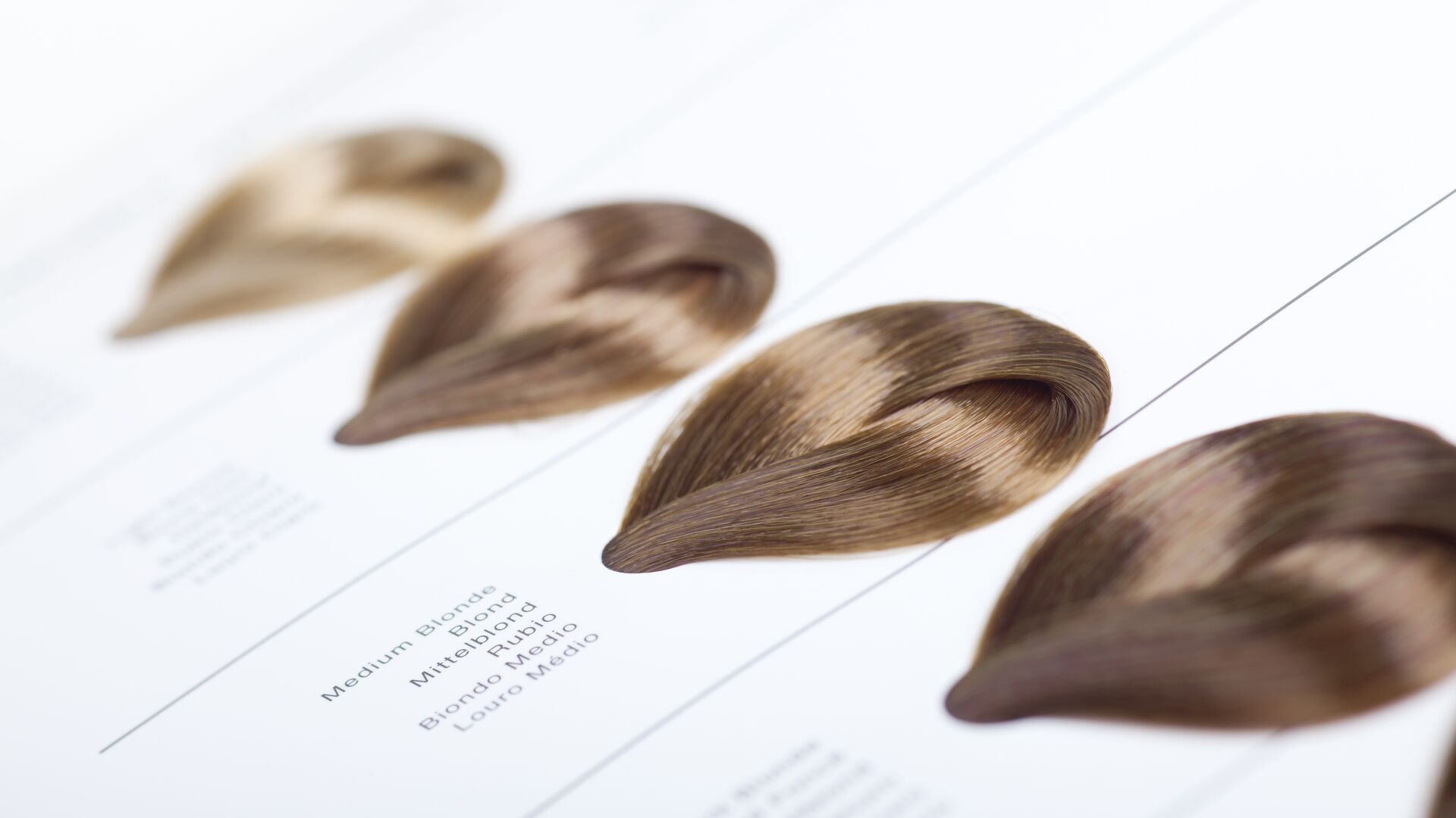 Hair color dye swatches against a white backdrop with short descriptions, medium blonde in a variety of languages. Meant to convey hair care, and hair coloring consumer markets.