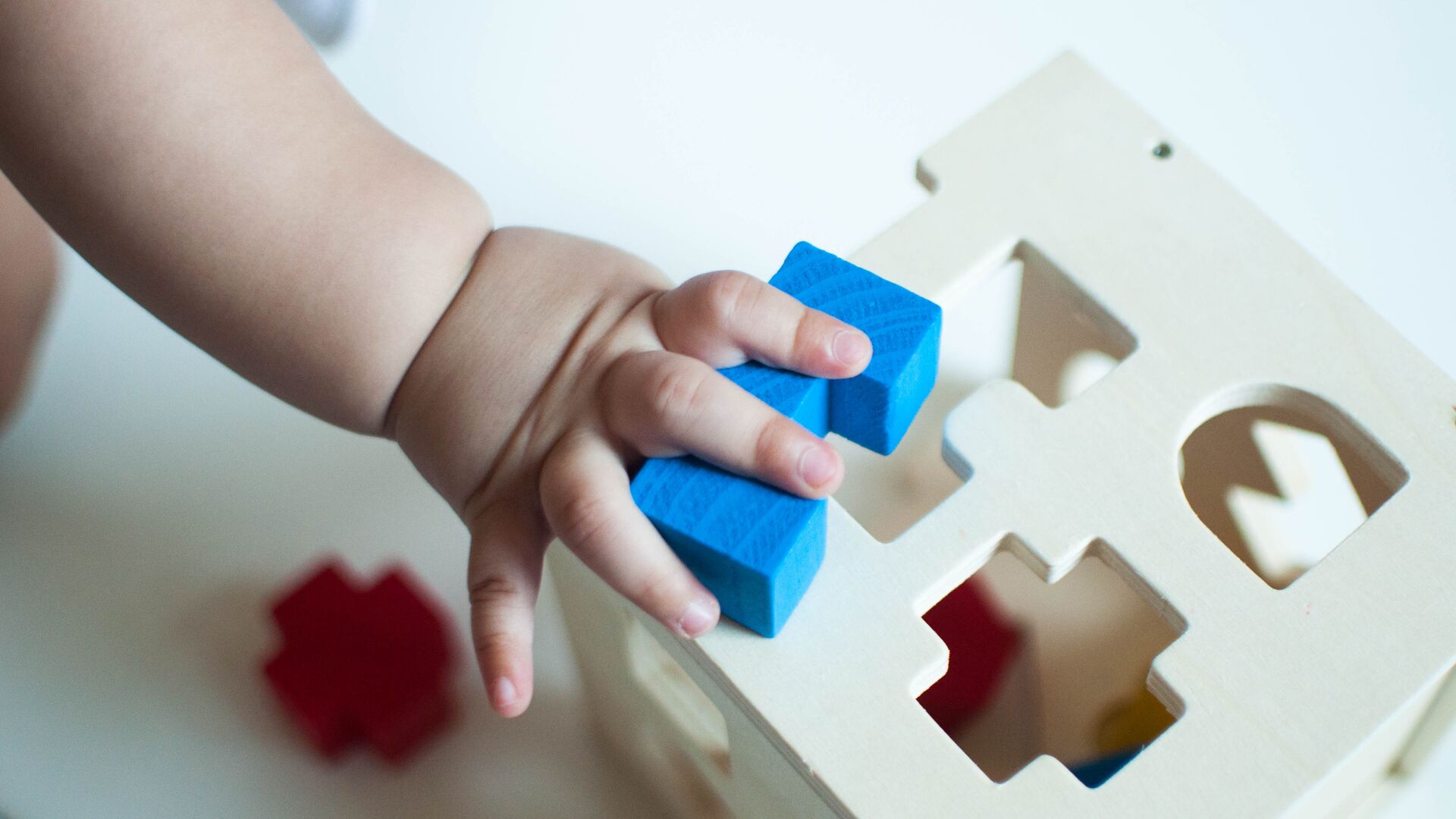 Baby placing a block as if it were a puzzle piece in its place. Representative of play and cognitive abilities in babies.