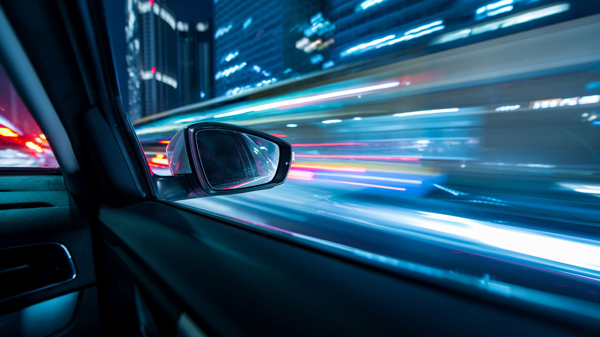 Representing the future of mobility is an image of a city scape flying by in patterns of lights outside of a car window.
