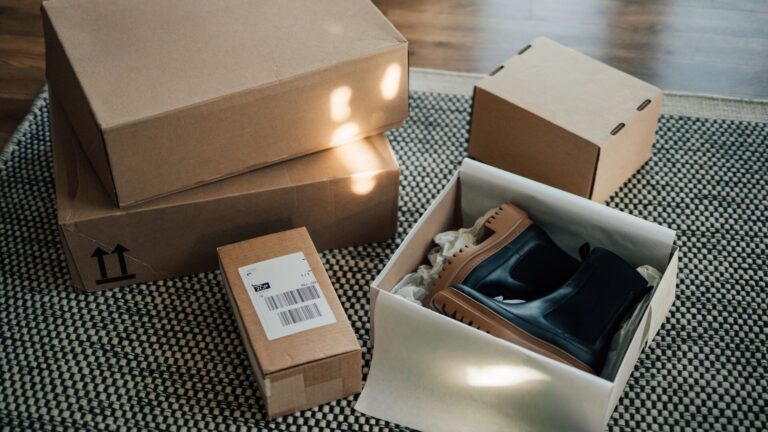 Boxes of clothes obtained through online shopping, one of them is opened and contains woman's boots. The sunlight is drawn in, meant to represent balancing sustainability with fashion.