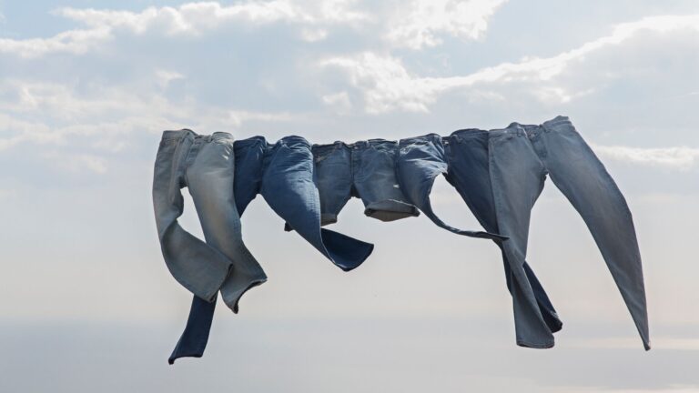Blue jeans hanging on a clothing rack against a sunny cloudy sky representing our recent podcast with Levi's