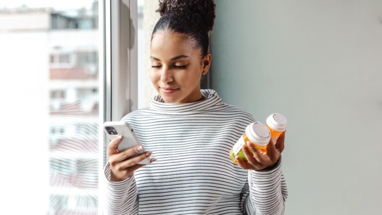 A woman checking her medicaion against her telehealth prescription on her phone. Representing a leading telehealth and digital health company.