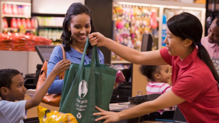 Mixed race woman using reusable bag in department store check out line.